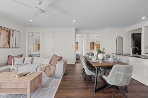 Ein modernes Wohnzimmer mit Sofa, Couchtisch und Essbereich mit Stühlen und Tisch, gedeckt für eine Mahlzeit.
