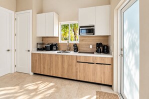 Una cocina moderna con armarios de madera, microondas integrado y cafetera.