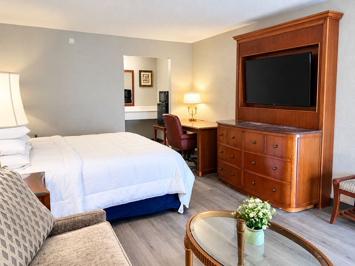 A hotel room with a bed, a desk, a television, and a chair.