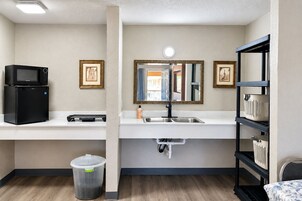 Una kitchenette compacta con microondas, pileta y un pequeño basurero.