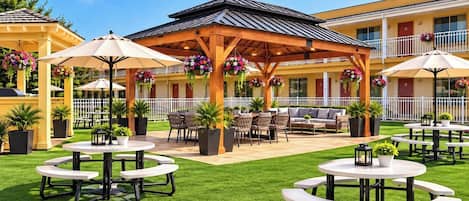 A courtyard with outdoor seating, a covered area, and a building with balconies.