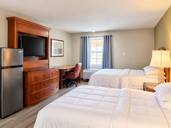 A hotel room with a bed, a desk, a chair, a television, and a refrigerator. - Remington Inn and Extended Stay (Little Rock)