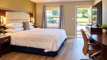 A hotel room with a bed, bedside table, lamp, and a desk with a chair.