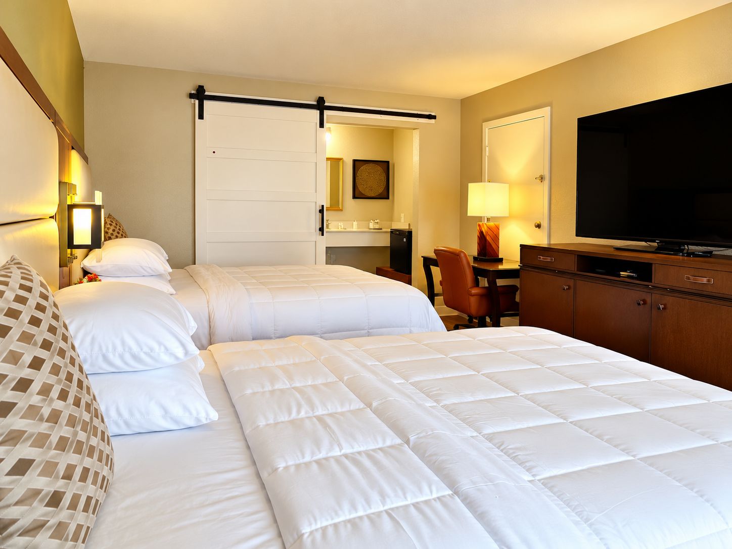 A hotel room with two beds, a desk, a television, and a wardrobe.