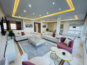 A modern living room with a sofa set, a coffee table, and a small round table. - 3-bedroom apartment in soothing Sousse with AC for relaxing stays (Susah)