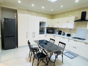 A modern kitchen with white cabinets, a black refrigerator, a marble countertop, and a gas stove. - 3-bedroom apartment in soothing Sousse with AC for relaxing stays (Susah)