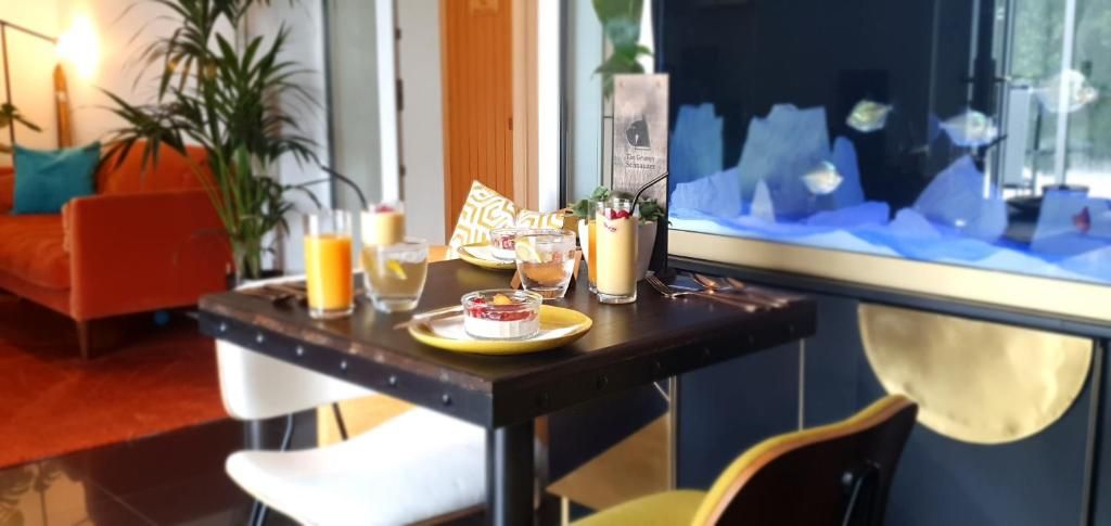 Un coin repas avec une table dressée pour deux personnes, où l’on propose une variété de boissons et un dessert.