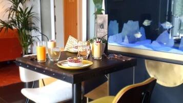 Un coin repas avec une table dressée pour deux personnes, où l’on propose une variété de boissons et un dessert.