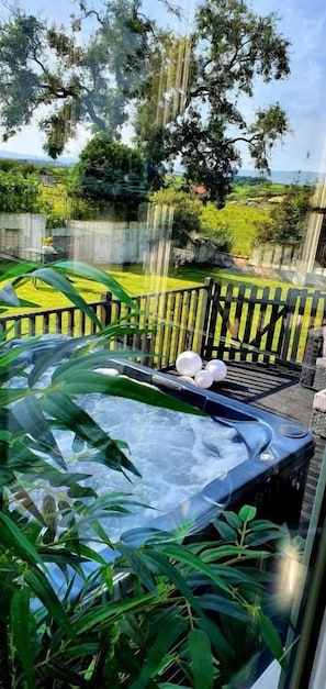 Un jacuzzi rodeado de exuberante vegetación, con cerca de madera y una vista despejada del paisaje.