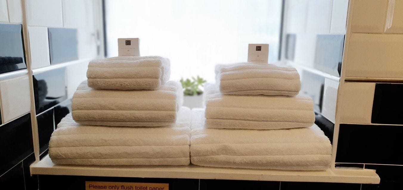 A stack of white towels on a table with a sign that reads 'Please only flush toilet paper.'