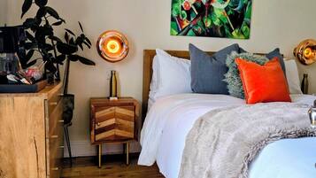 A bedroom with a bed, bedside table, lamp, and a wall-mounted sign.