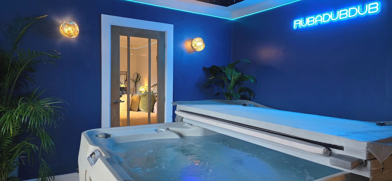 Une pièce avec un jacuzzi, un néon et une porte donnant sur une salle de bain.