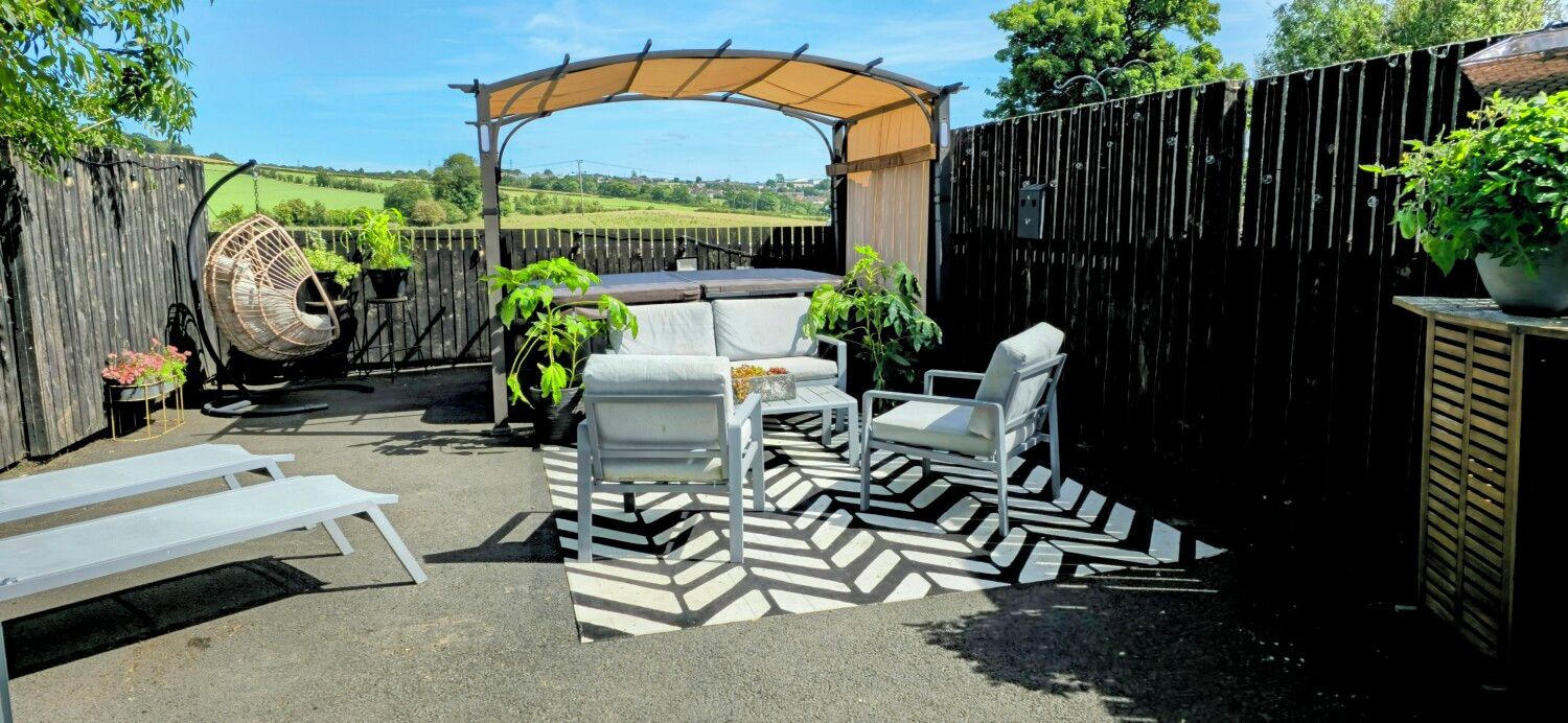 A patio with outdoor furniture, a swing chair, and a pergola providing shade.