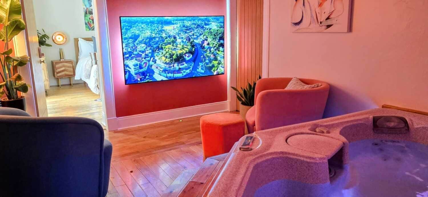A room with a large flat-screen TV, a massage chair, and a small table with a remote control.