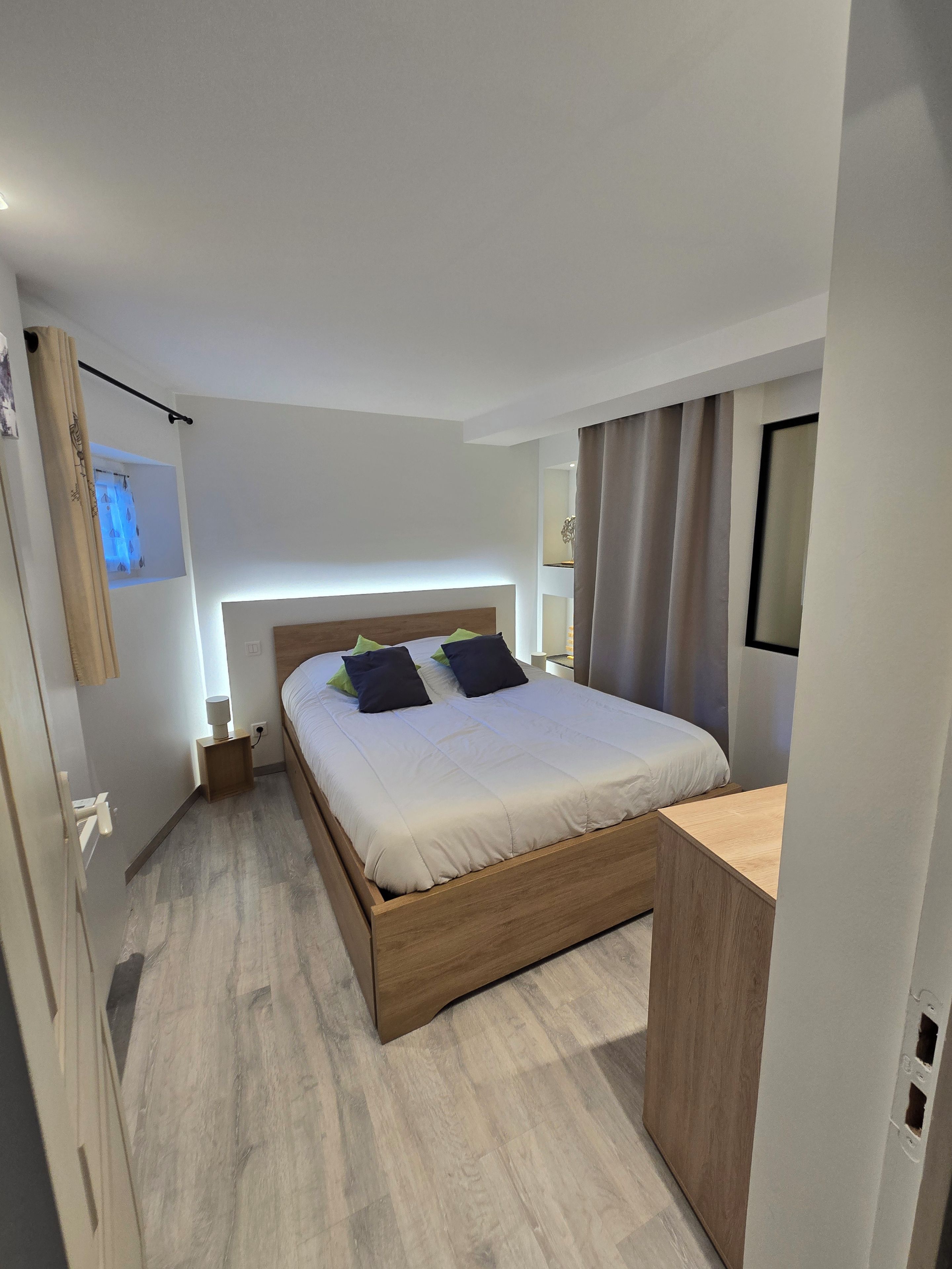 A modern bedroom with a wooden bed, bedside tables, and a built-in desk.