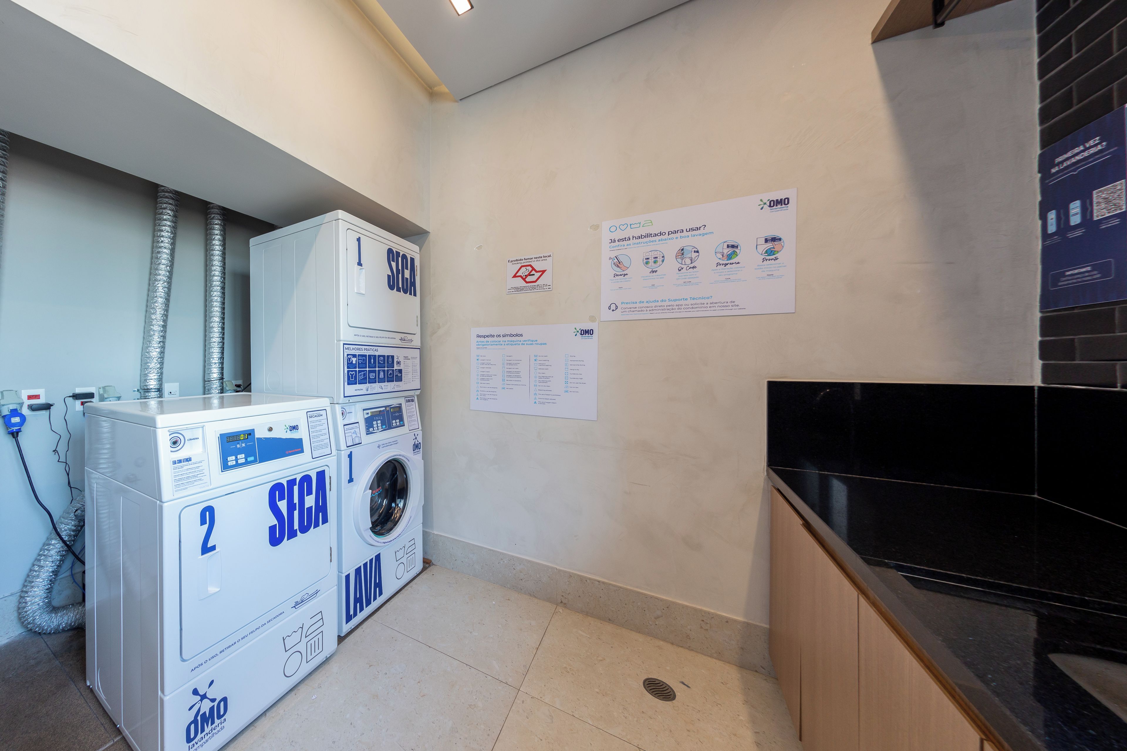 A laundry area with two SECA washing machines, a wall-mounted dryer, and a black countertop.