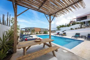 A poolside area with a wooden table and lounge chairs. - Casa Pasha - Apartment Havana - Jan Thiel (Jan Thiel)