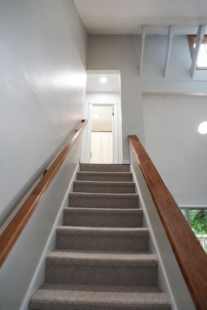 A staircase with carpeted steps and wooden handrails, leading to a door at the top. - Charming 3-bedroom house in peaceful Monson (Monson)