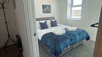 Een slaapkamer met een bed, een raam en een kapstok.