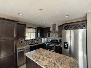 A kitchen with dark wood cabinets, a stainless steel refrigerator, a built-in oven, and a window with a view of the outdoors. - Cozy home: waterfront w/beach on Lake Madison.  4bd/2baths sleeps 8 comfortably (Madison)