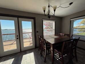A dining area with a view of the water, a chandelier, and a sliding glass door.