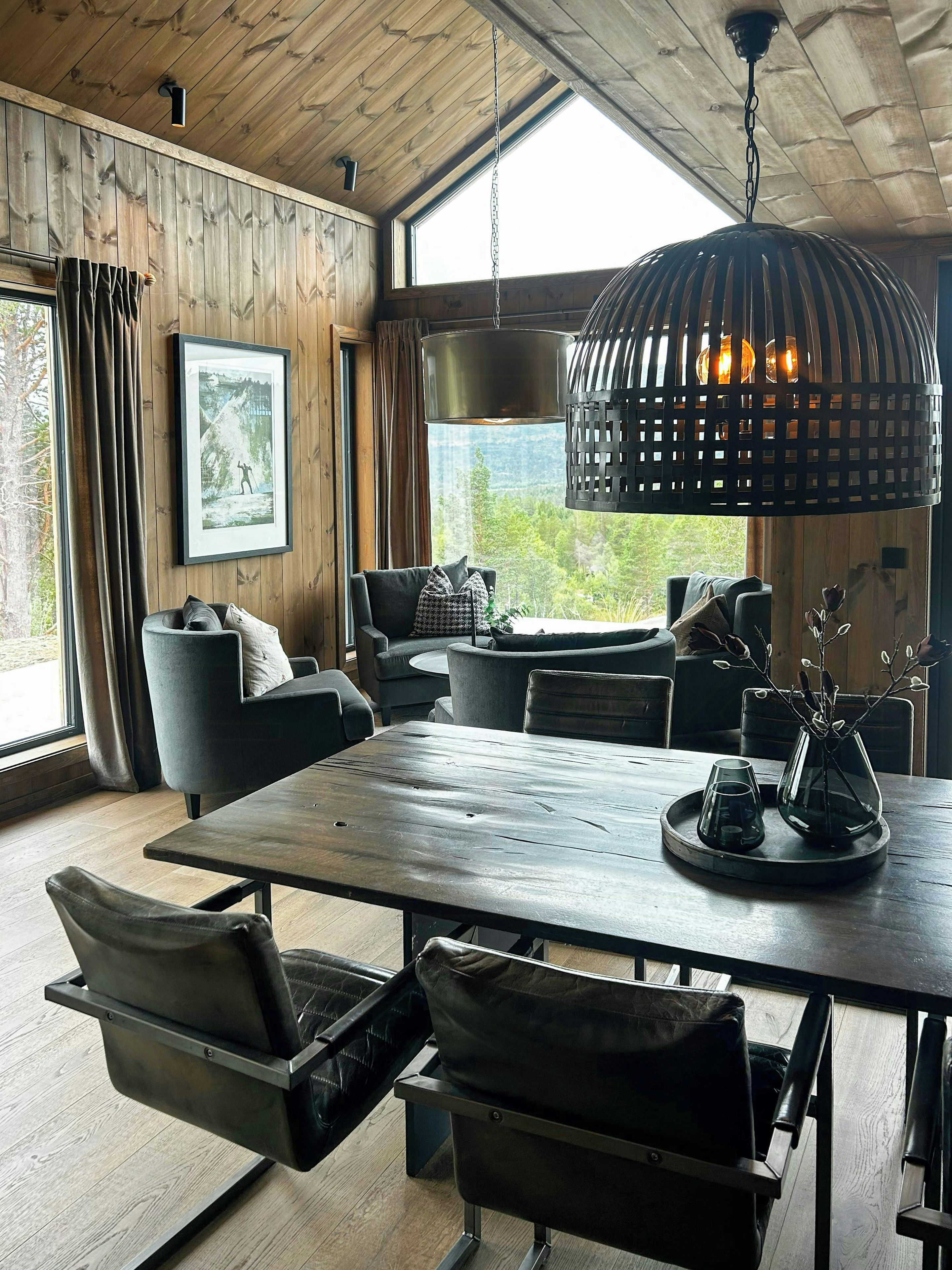 Ein modernes Interieur mit Holzbalkendecke, einem großen Esstisch und Sitzgelegenheiten.