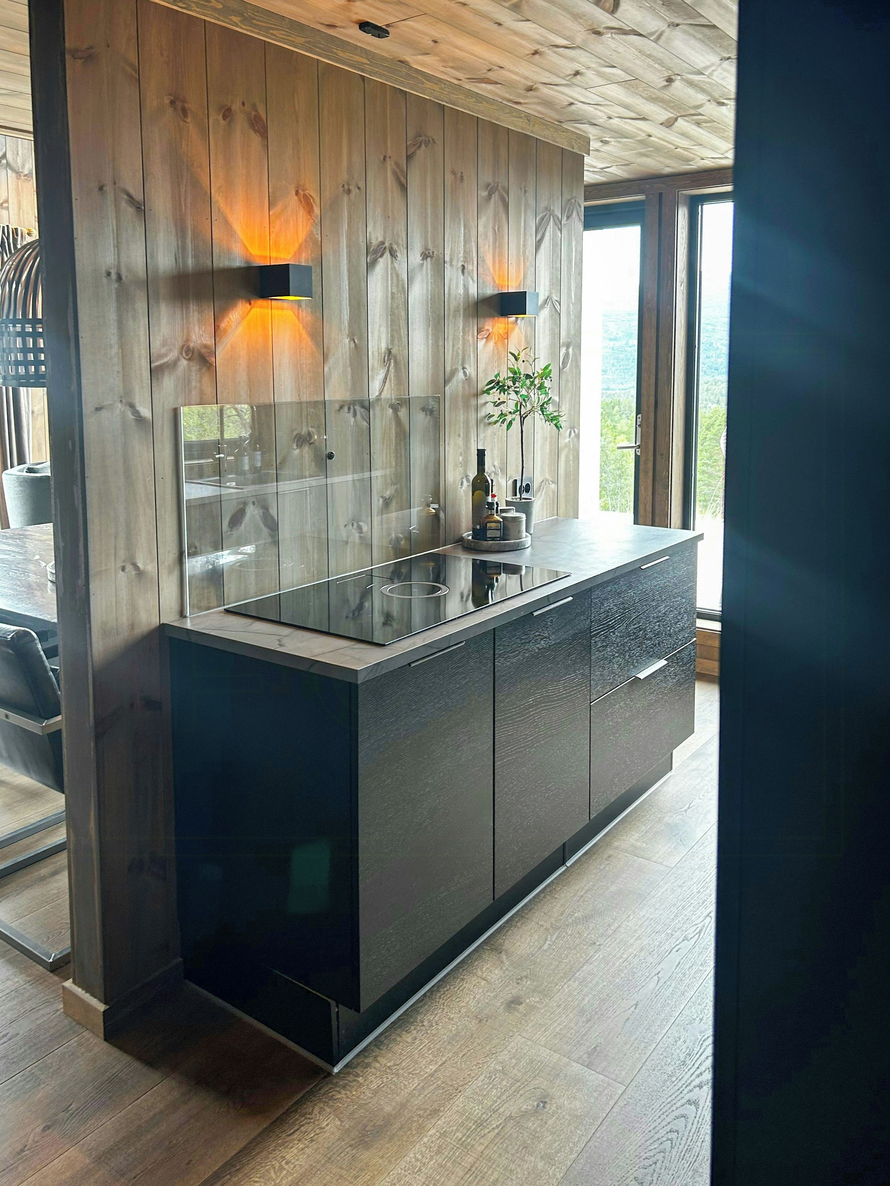 Una cucina moderna con una parete a parete in legno, un'isola in vetro e vista sull'esterno.
