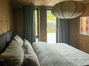 Een kamer met een bed, gordijnen, een raam en een plafondlamp.