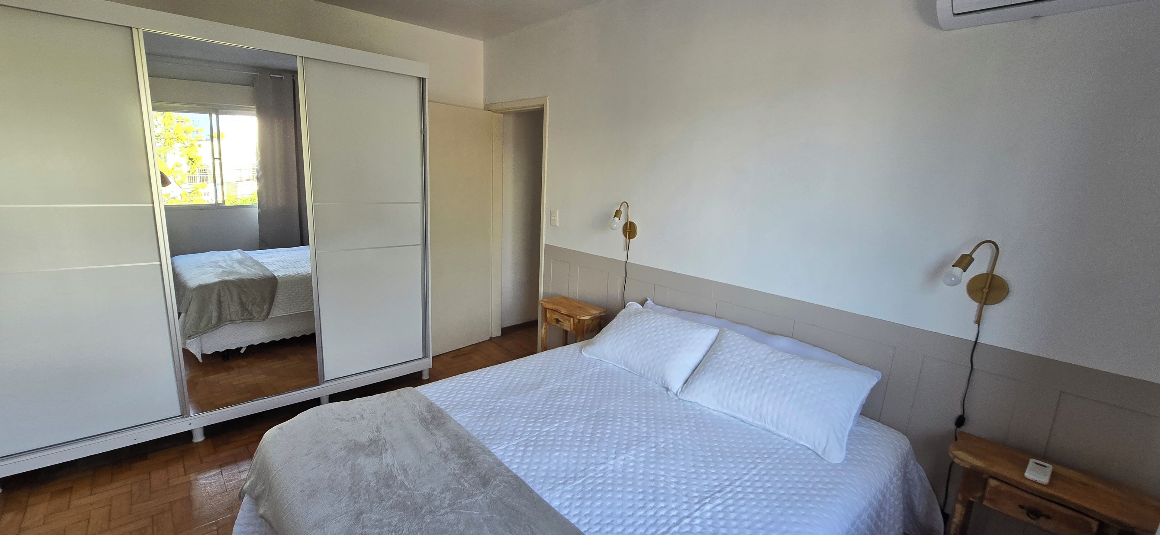 Un dormitorio con cama, armario, mesita de noche y lámpara de pared.