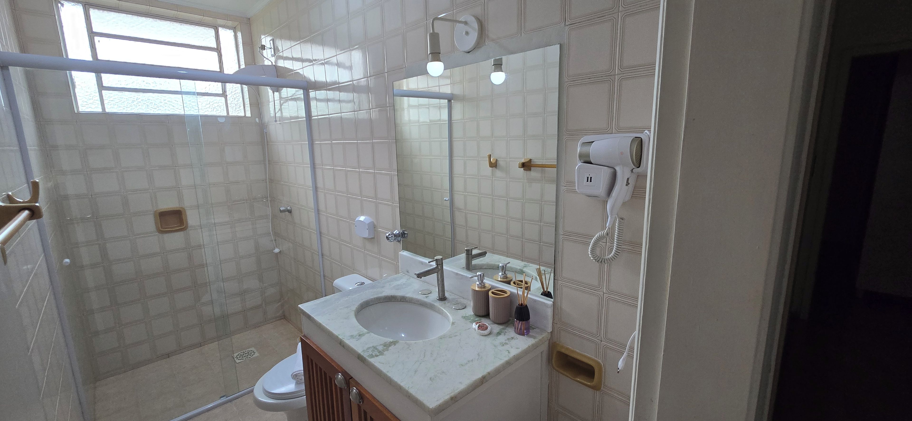 Une salle de bain équipée d’une douche, de toilettes, d’un lavabo et d’un miroir.