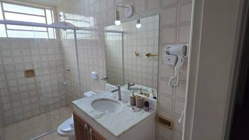 Une salle de bain équipée d’une douche, de toilettes, d’un lavabo et d’un miroir.