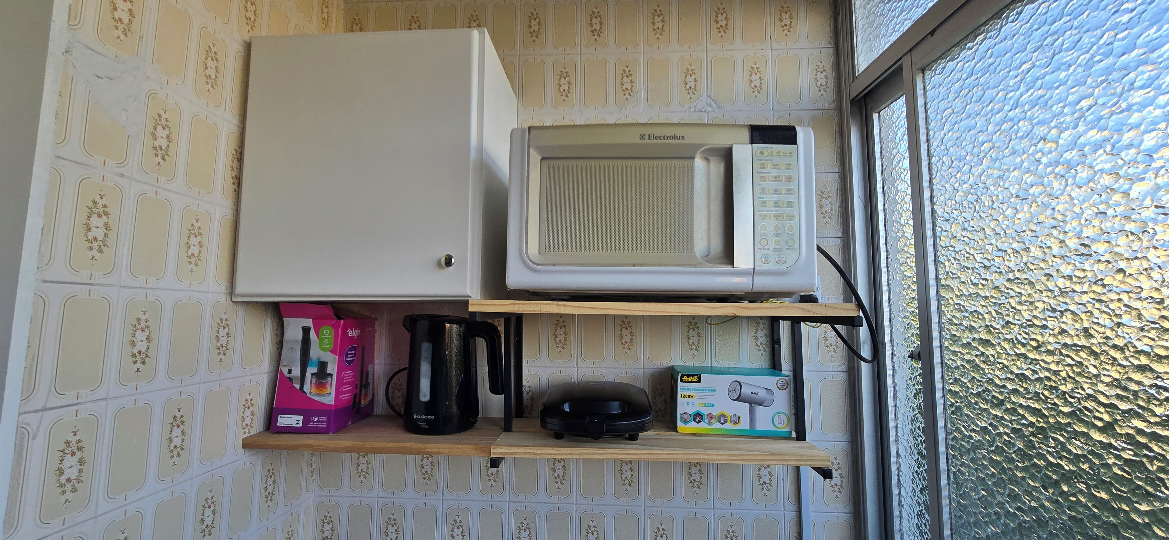 A kitchenette with a microwave, a coffee maker, and a box of tea.