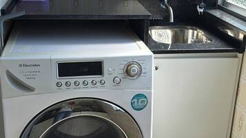 Una cocina funcional con lavadora, microondas y lavamanos.