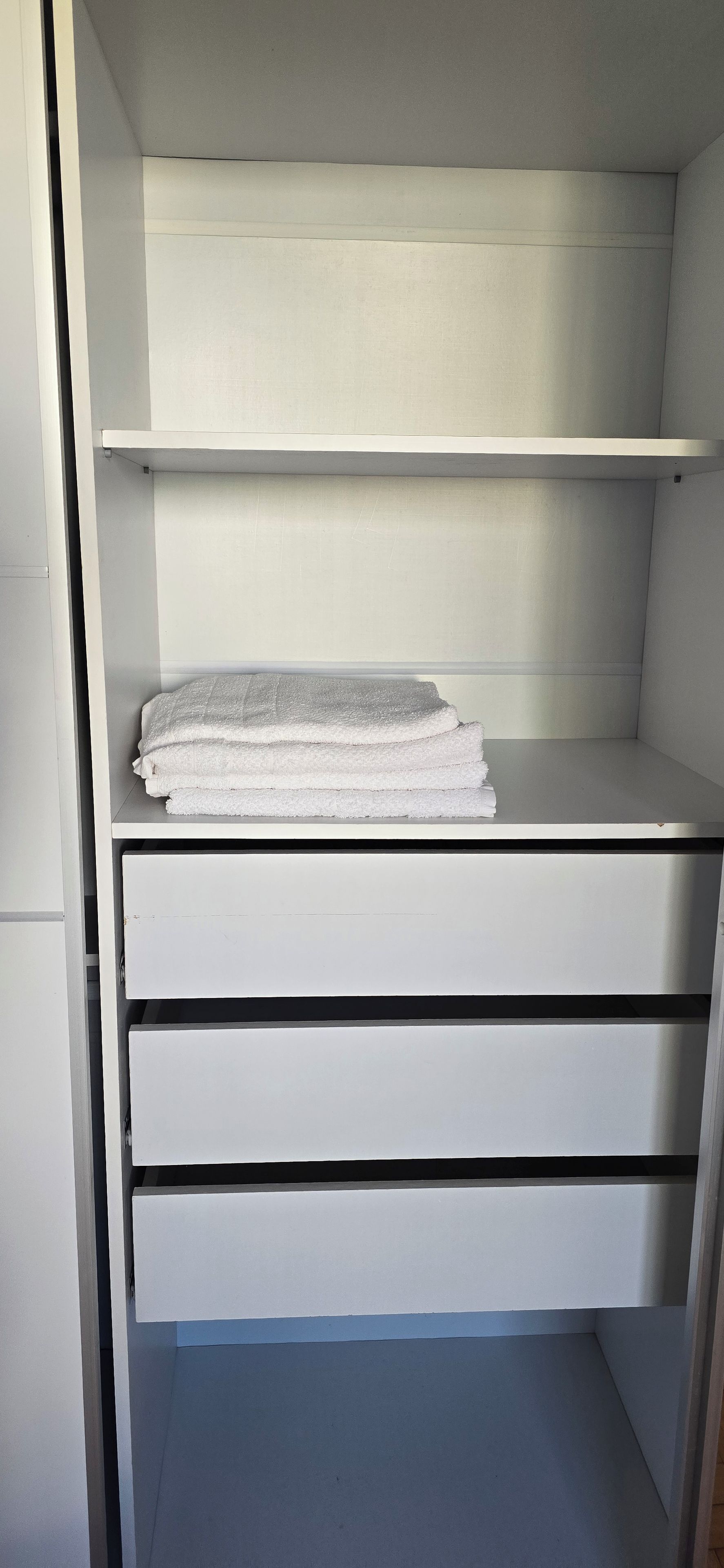A white wardrobe with multiple shelves and drawers.