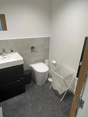 Ein kleines Badezimmer mit Waschbecken, Toilette und Stauraumschrank.