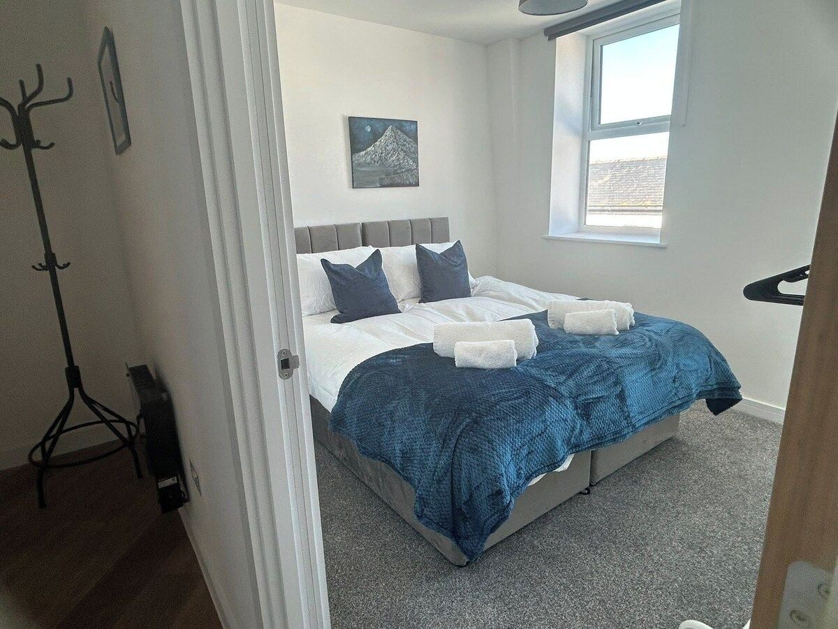 A bedroom with a bed, a window, and a coat rack.