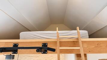 Ein Schlafzimmer im Loft-Stil mit einer Holzleiter, die zu einem Stockbett führt, einer Deckenleuchte und einem Fenster.