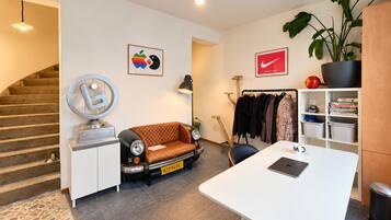 Ein moderner Wohnraum mit einer Couch, einem Schreibtisch, einem Kleiderständer und einer Treppe.