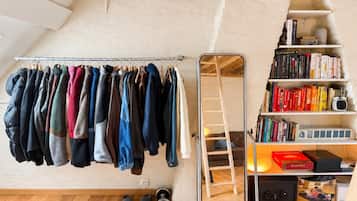 Una habitación con un perchero, una escalera y una estantería con libros y un radio.