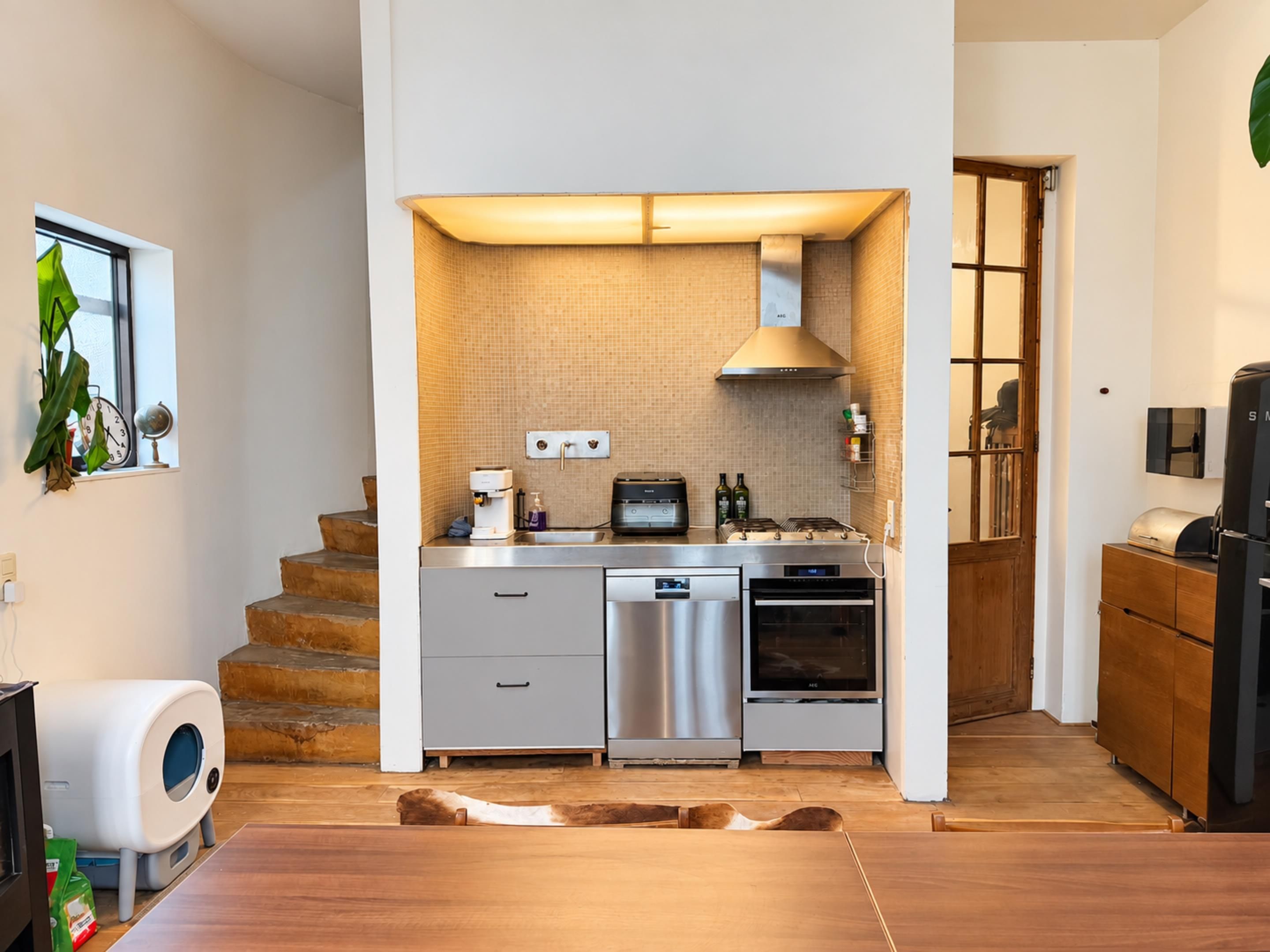 Una cucina compatta con forno a incasso, macchina del caffè e tostapane.