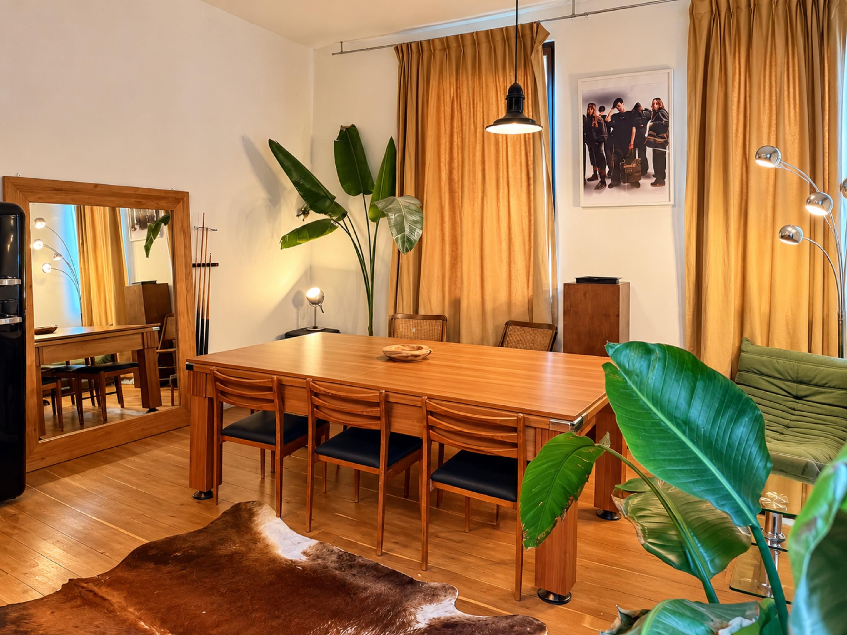 Een eetgedeelte met een houten tafel, stoelen en een grote plant.