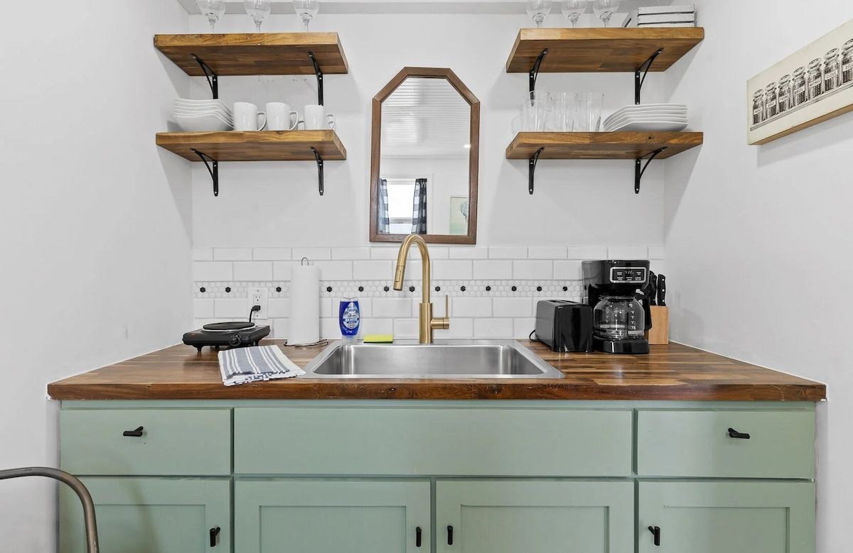 A kitchen with a wooden countertop, a sink, and a coffee maker.