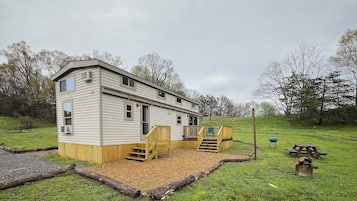 Een gelijkvloers houten vakantiehuisje met een terras en een picknicktafel in een gazon.