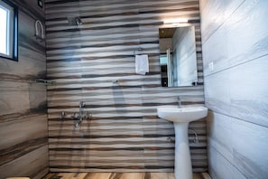 Et badeværelse med et moderne design, med et træmønster på væggen, en vask og et bruseområde.