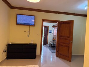 Un pasillo con una puerta de madera, un mueble de entretenimiento negro y un televisor montado en la pared.