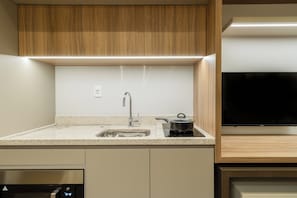 Une cuisine moderne équipée d’une cuisinière intégrée, d’un évier et d’un téléviseur à écran plat.