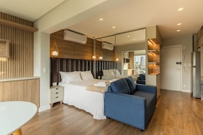 Une chambre à coucher moderne avec un lit, des tables de chevet, un canapé et un grand miroir.