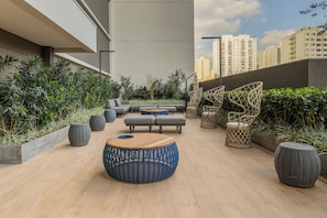 Une terrasse sur le toit, dotée d’un espace extérieur aménagé avec des sièges, des jardinières et offrant une vue sur les bâtiments de la ville.