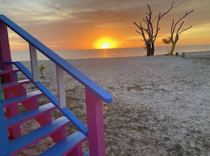 A staircase leading to a beach with a sunset in the background. - Bahama Dreamin' Upstairs Oceanfront Villa 2/2 (Long Island)