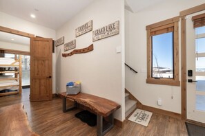 A hallway with wooden flooring, a bench, a metal basket, and wooden signs on the wall. - Mountain Escape With Hot Tub & Fire Pit (Fraser)